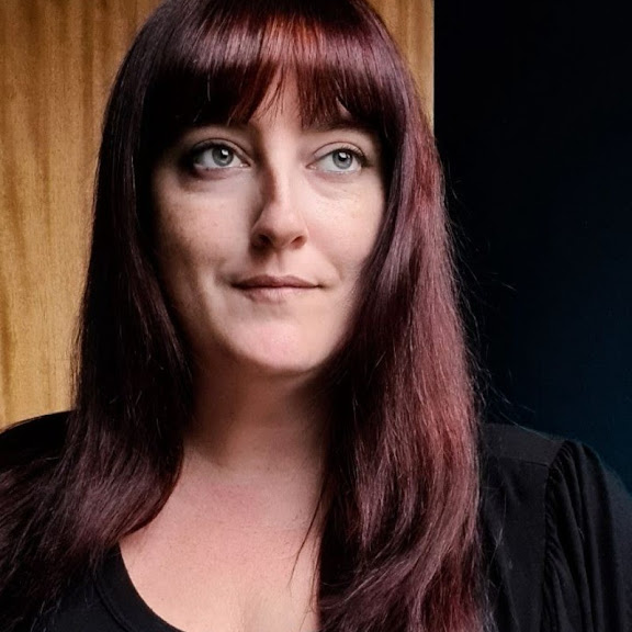 a 40-something white lady with long hair and bangs, gazing into the future